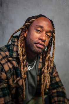 a man with dreadlocks sitting in front of a wall