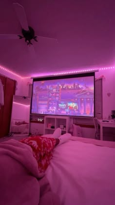 a bedroom with pink lighting and a large screen