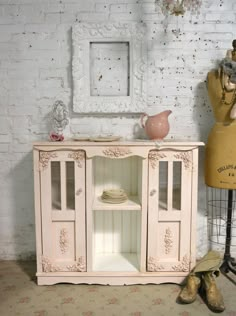 an old fashioned china cabinet next to a mannequin's head and vase