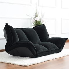 a black couch sitting on top of a white rug next to a potted plant