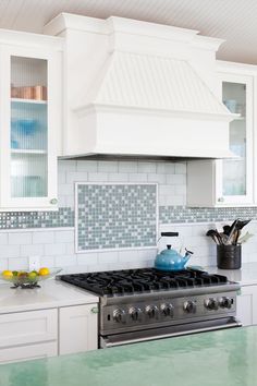 a stove top oven sitting inside of a kitchen next to white cabinets and counter tops