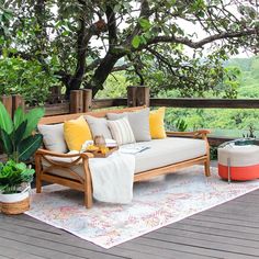 a wooden couch sitting on top of a wooden deck next to a lush green forest