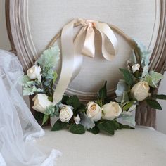 a wreath with flowers and greenery is sitting on a chair next to a veil