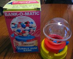 a toy gum ball machine next to a bank - o - matic box on a table