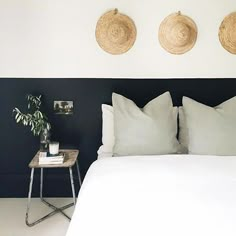 a bed with two baskets on the wall above it and a small table next to it