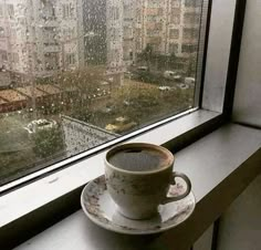 a coffee cup sitting on top of a saucer next to a window