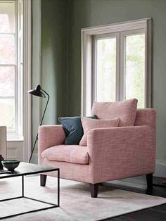 a living room filled with furniture and two windows next to each other on top of a rug