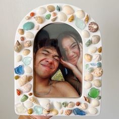 a man and woman are smiling in a frame made out of seashells