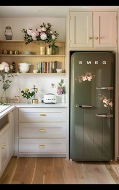 an old refrigerator is in the middle of a kitchen with white cabinets and wood floors