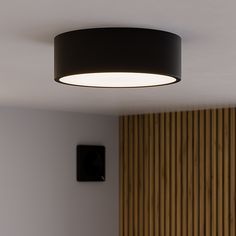 a round light fixture hanging from the ceiling in a room with wood paneled walls