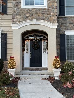 a house with christmas decorations on the front door and wreaths hanging from the windows