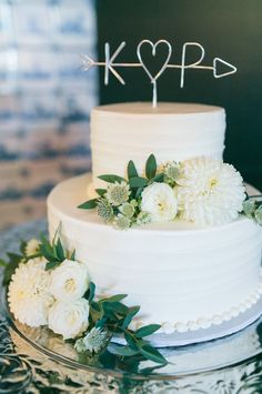 a white wedding cake with flowers and an arrow on top