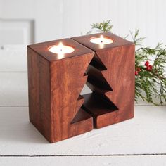 two candles are placed in a wooden box with a christmas tree cut out from it