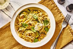 a white bowl filled with pasta and veggies on top of a yellow napkin