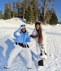 two people standing in the snow with skis on