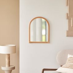 a living room with a chair, mirror and lamp on the wall next to it