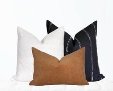 three pillows sitting on top of a bed next to each other in front of a white wall