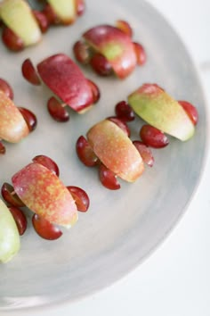 several pieces of fruit are arranged on a white plate with red and green candies