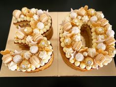 two cakes decorated with shells and pearls on top of a cardboard box next to each other