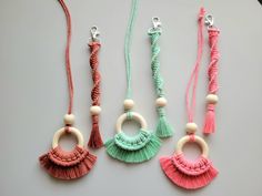 three necklaces with tassels and wooden beads on a gray surface, one in pink, the other in green