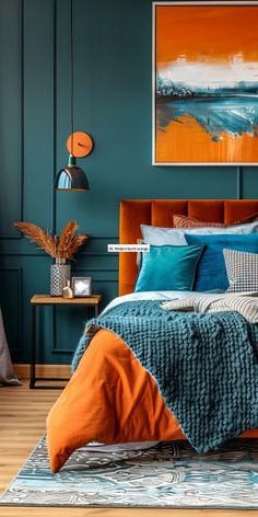 a bed with blue and orange pillows in a bedroom next to a painting on the wall