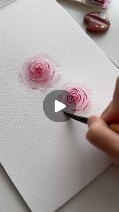 someone is painting roses with watercolors on paper