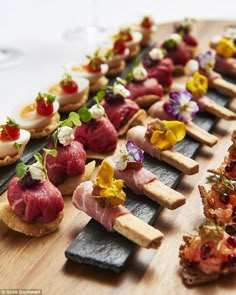 a wooden board topped with lots of different types of appetizers on top of it