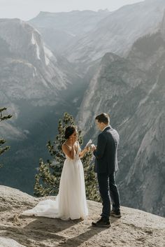 a bride and groom standing on top of a mountain