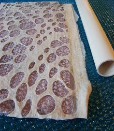 rolled up dough sitting on top of a blue mat next to a roll of paper