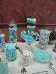 a table topped with lots of blue and white candies next to silver spoons