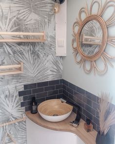 a bathroom sink sitting under a mirror next to a wall mounted faucet and wooden shelves