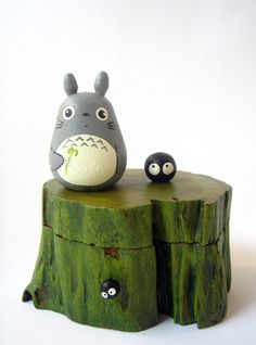 a totoro figurine sitting on top of a piece of tree stump