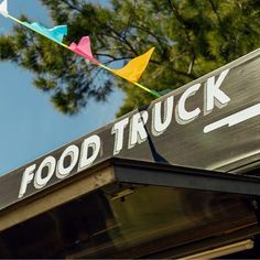 a food truck sign with colorful kites in the sky above it's roof