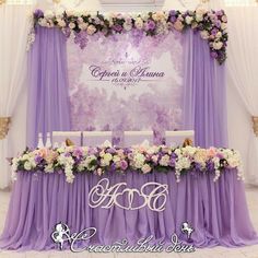 the table is set up with purple and white flowers on it for an elegant wedding reception