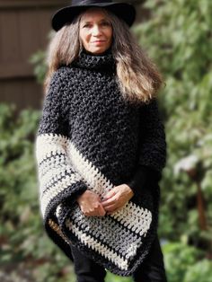 a woman is wearing a black and white crocheted ponchy with boots