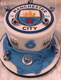 the cake is decorated with soccer balls and manchester city crest on it's side