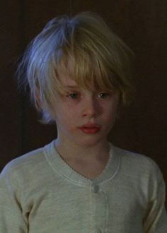 a young boy with blonde hair is looking at the camera