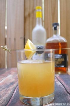 a glass filled with an alcoholic drink on top of a wooden table