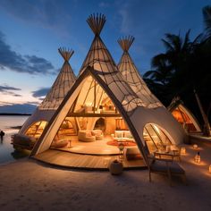 a white tent sitting on top of a sandy beach next to the ocean at night