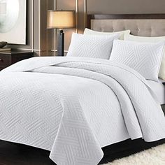 a bed with white bedspread and pillows in a room