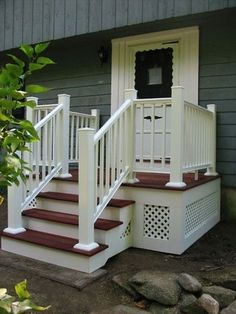 a white porch with red steps leading up to the front door and side entry area