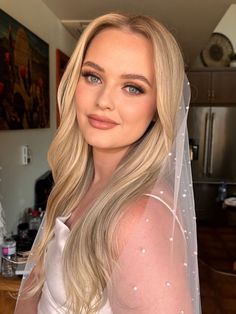 a woman with blonde hair wearing a white veil and posing for a photo in her kitchen