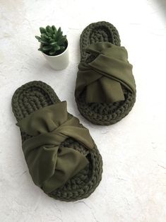 a pair of green slippers sitting on top of a white floor next to a potted plant