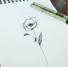 a drawing of a flower on paper next to a marker and pen with the word love written in it