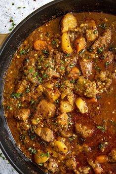 a pot filled with stew and potatoes on top of a table