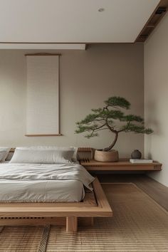 a large bed sitting under a window next to a bonsai tree in a bedroom