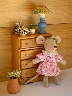 a stuffed mouse is standing next to a dresser