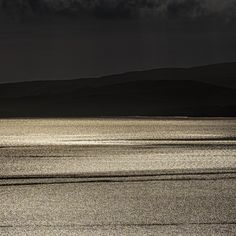 a lone boat floating in the ocean under a dark sky