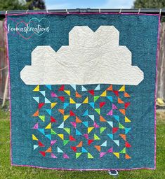 a quilted wall hanging on a clothesline with an image of a cloud in the sky