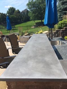 an outdoor table with chairs and umbrellas in the background